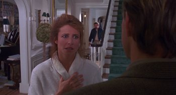 Movie still from “Desperate Hours” (1990), directed by Michael Cimino – A woman in a bathrobe talking to a man in front of a staircase; Medium shot, Over the shoulder angle
