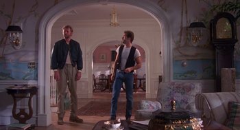 Movie still from “Desperate Hours” (1990), directed by Michael Cimino – Two men standing in a living room , one of whom is holding a saxophone; Wide shot, Low angle