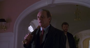 Movie still from “Desperate Hours” (1990), directed by Michael Cimino – An older man holding a baseball bat in front of another man; Medium shot, Low angle