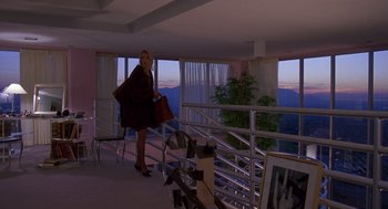 Movie still from “Desperate Hours” (1990), directed by Michael Cimino – A woman with a purse walking down the stairs; Wide shot, High angle