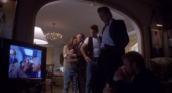Movie still from “Desperate Hours” (1990), directed by Michael Cimino – A group of people standing around in a living room; Wide shot, Over the shoulder angle