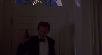 Movie still from “Desperate Hours” (1990), directed by Michael Cimino – A man in a tuxedo holding a beer in his hand; Medium shot, Low angle