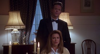 Movie still from “Desperate Hours” (1990), directed by Michael Cimino – A man and a woman standing next to each other in front of a candle; Medium shot, Low angle