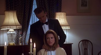 Movie still from “Desperate Hours” (1990), directed by Michael Cimino – A man standing next to a woman in front of candles; Medium shot, Over the shoulder angle