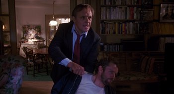 Movie still from “Desperate Hours” (1990), directed by Michael Cimino – A man in a suit and tie standing next to another man in a white shirt; Medium shot, Low angle