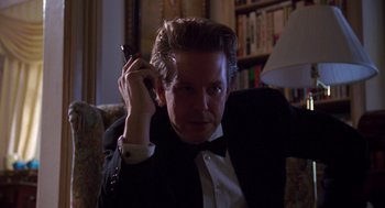 Movie still from “Desperate Hours” (1990), directed by Michael Cimino – A man in a tuxedo is holding a cell phone to his ear; Close Up shot, Low angle