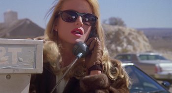 Movie still from “Desperate Hours” (1990), directed by Michael Cimino – A woman in sunglasses talking on a cell phone; Close Up shot, Low angle