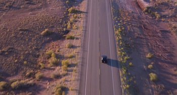 Movie still from “Desperate Hours” (1990), directed by Michael Cimino – An aerial view of a car driving down a road; Extreme Wide shot, Overhead angle