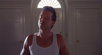 Movie still from “Desperate Hours” (1990), directed by Michael Cimino – A man in a white tank top is standing in front of a door; Close Up shot, Low angle