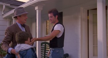 A man shaking hands with another man outside a house