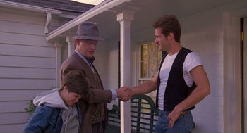 Movie still from “Desperate Hours” (1990), directed by Michael Cimino – Two men shaking hands while a young boy watches; Medium shot, Over the shoulder angle