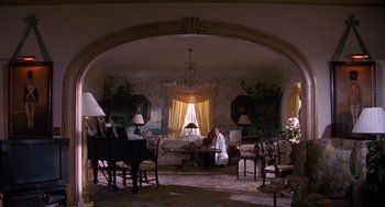 Movie still from “Desperate Hours” (1990), directed by Michael Cimino – A woman sitting on a couch in a living room; Extreme Wide shot, High angle