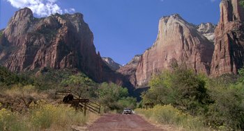 Movie still from “Desperate Hours” (1990), directed by Michael Cimino – A car driving down a dirt road in the mountains; Extreme Wide shot, Low angle