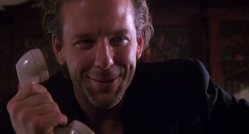 Movie still from “Desperate Hours” (1990), directed by Michael Cimino – A person smiling while holding a phone; Close Up shot, Low angle