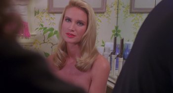 Movie still from “Desperate Hours” (1990), directed by Michael Cimino – A woman with long blonde hair sitting in front of a bathroom mirror; Close Up shot, Over the shoulder angle