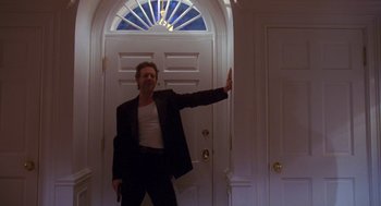 Movie still from “Desperate Hours” (1990), directed by Michael Cimino – A man holding a gun standing in front of a door; Medium shot, Low angle