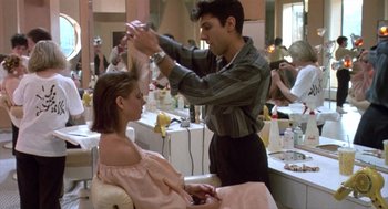 Movie still from “Desperately Seeking Susan” (1985), directed by Susan Seidelman – A woman getting her hair cut by a man; Medium shot, Over the shoulder angle