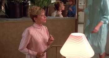 Movie still from “Desperately Seeking Susan” (1985), directed by Susan Seidelman – A woman standing in front of a lamp in a room; Medium shot, Over the shoulder angle
