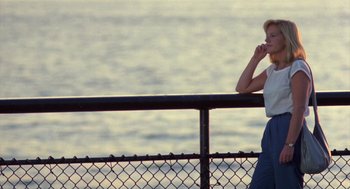 Movie still from “Desperately Seeking Susan” (1985), directed by Susan Seidelman – A woman standing next to a railing near the ocean; Medium shot, Low angle