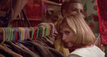 Movie still from “Desperately Seeking Susan” (1985), directed by Susan Seidelman – A woman sitting next to a man in front of clothes; Close Up shot, Over the shoulder angle