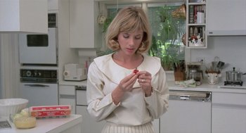 Movie still from “Desperately Seeking Susan” (1985), directed by Susan Seidelman – A woman in a white shirt is holding a strawberry; Medium shot, Low angle