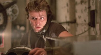 Movie still from “Desperately Seeking Susan” (1985), directed by Susan Seidelman – A young man is looking at the camera while holding a phone; Close Up shot, Low angle