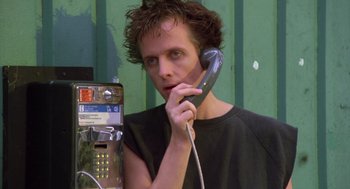 Movie still from “Desperately Seeking Susan” (1985), directed by Susan Seidelman – A man holding a phone up to his ear; Close Up shot, Low angle
