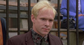 Movie still from “Desperately Seeking Susan” (1985), directed by Susan Seidelman – A man with blonde hair wearing a suit and tie; Close Up shot, Low angle