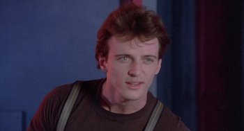 Movie still from “Desperately Seeking Susan” (1985), directed by Susan Seidelman – A person wearing a brown shirt and suspenders; Close Up shot, Low angle