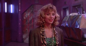 Movie still from “Desperately Seeking Susan” (1985), directed by Susan Seidelman – A woman in a green dress and a brown jacket; Close Up shot, Over the shoulder angle