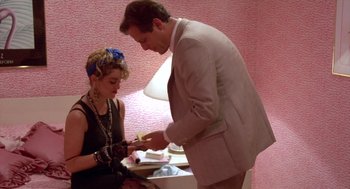 Movie still from “Desperately Seeking Susan” (1985), directed by Susan Seidelman – A man and a woman are looking at something on a table; Medium shot, Over the shoulder angle