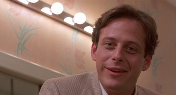 Movie still from “Desperately Seeking Susan” (1985), directed by Susan Seidelman – A person wearing a suit and smiling; Close Up shot, Low angle