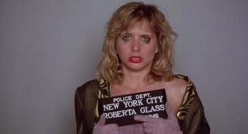 Movie still from “Desperately Seeking Susan” (1985), directed by Susan Seidelman – A woman holding up a sign that says " new york city roberta glass "; Close Up shot, Over the shoulder angle