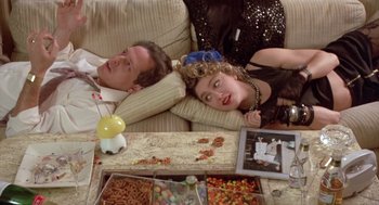 Movie still from “Desperately Seeking Susan” (1985), directed by Susan Seidelman – A man and a woman laying on a couch next to each other; Medium shot, Overhead angle