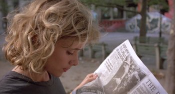 Movie still from “Desperately Seeking Susan” (1985), directed by Susan Seidelman – A woman is reading a newspaper in a park; Close Up shot, Over the shoulder angle