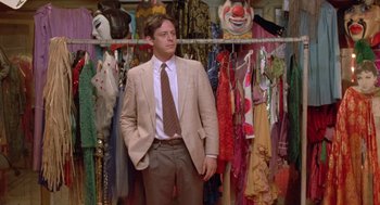 Movie still from “Desperately Seeking Susan” (1985), directed by Susan Seidelman – A man in a suit standing in front of a closet full of clothes; Medium shot, Low angle