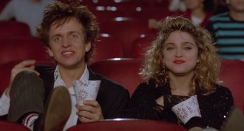 Movie still from “Desperately Seeking Susan” (1985), directed by Susan Seidelman – A man and a woman sitting next to each other; Medium shot, Low angle