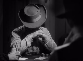 Movie still from “Destry Rides Again” (1939), directed by George Marshall – A man with a hat sitting at a card table; Close Up shot, Over the shoulder angle