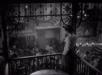 Movie still from “Destry Rides Again” (1939), directed by George Marshall – A man standing on the balcony of a restaurant; Wide shot, High angle