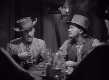 Movie still from “Destry Rides Again” (1939), directed by George Marshall – A couple of men sitting at a dinner table; Medium shot, Over the shoulder angle