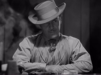 Movie still from “Destry Rides Again” (1939), directed by George Marshall – A black and white photo of a man wearing a hat; Close Up shot, Over the shoulder angle