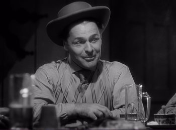 Movie still from “Destry Rides Again” (1939), directed by George Marshall – A man wearing a hat sitting at a dinner table; Close Up shot, Low angle