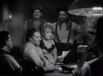 Movie still from “Destry Rides Again” (1939), directed by George Marshall – A group of people sitting around a table; Medium shot, Over the shoulder angle