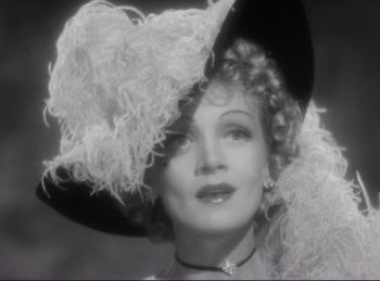 Movie still from “Destry Rides Again” (1939), directed by George Marshall – An old photo of a woman wearing a large hat; Close Up shot, Low angle