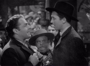 Movie still from “Destry Rides Again” (1939), directed by George Marshall – Two men wearing hats and one of them is holding his hand out to another man in a hat; Medium shot, Over the shoulder angle