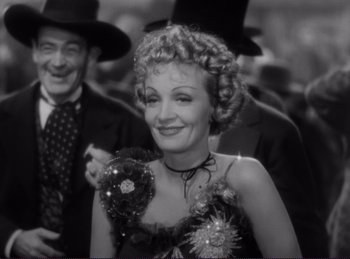 Movie still from “Destry Rides Again” (1939), directed by George Marshall – An old black and white photo of a woman in a dress; Close Up shot, Low angle