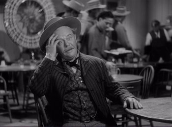 Movie still from “Destry Rides Again” (1939), directed by George Marshall – An older man sitting at a table in a restaurant; Medium shot, Over the shoulder angle