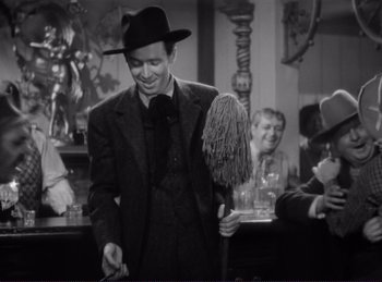 Movie still from “Destry Rides Again” (1939), directed by George Marshall – A black and white photo of a man in a suit and hat; Medium shot, Over the shoulder angle