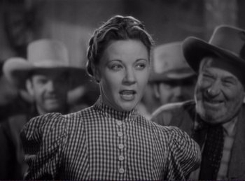 Movie still from “Destry Rides Again” (1939), directed by George Marshall – A black and white photo of a woman in a plaid dress; Medium shot, Low angle