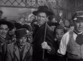 Movie still from “Destry Rides Again” (1939), directed by George Marshall – A man with a broom in a crowd of people; Medium shot, Low angle